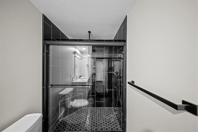 full bathroom featuring toilet, a stall shower, and a textured ceiling