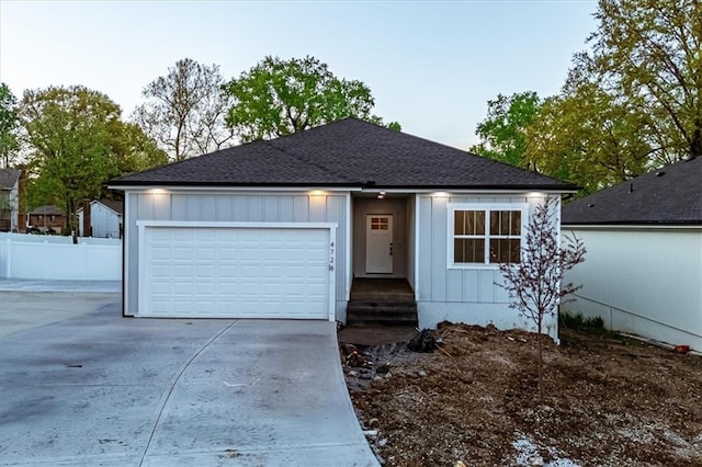 ranch-style home with concrete driveway, roof with shingles, a garage, fence, and board and batten siding