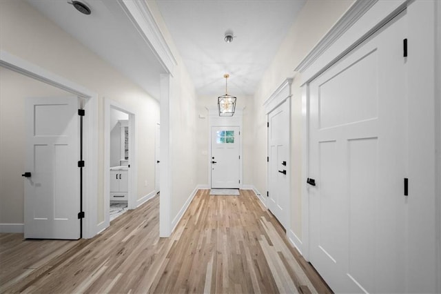 entryway featuring light wood-type flooring, baseboards, and a chandelier