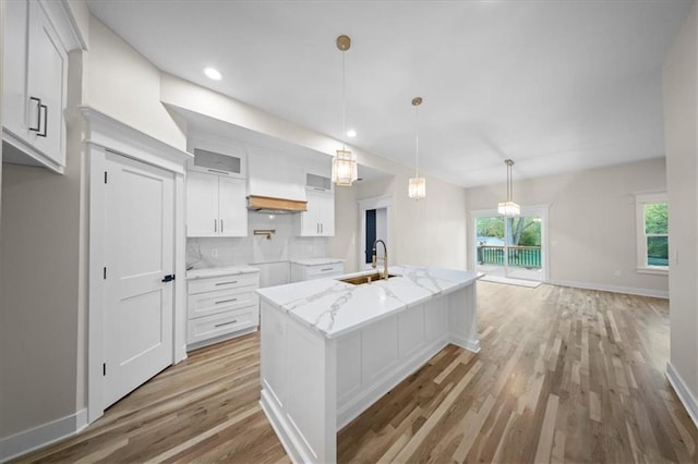 kitchen with light wood-type flooring, white cabinets, plenty of natural light, a sink, and recessed lighting