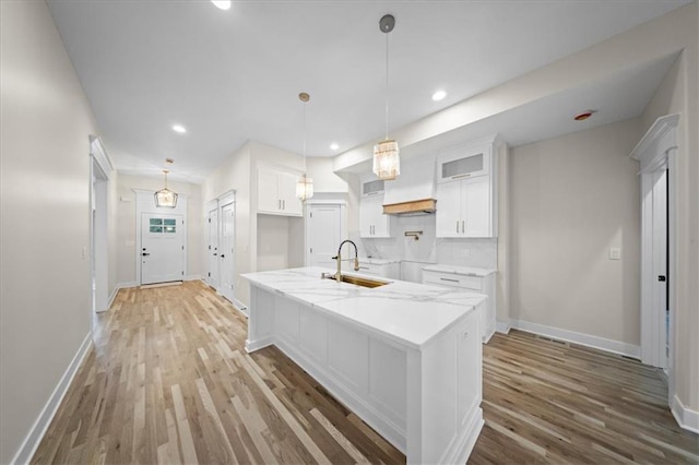 kitchen featuring a sink, white cabinets, baseboards, light wood finished floors, and recessed lighting