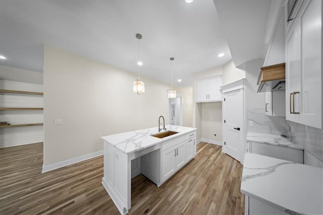 kitchen with a sink, baseboards, wood finished floors, white cabinets, and recessed lighting