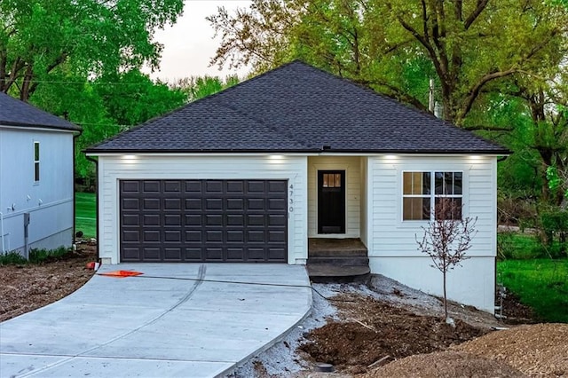 ranch-style home featuring concrete driveway, a garage, and a shingled roof