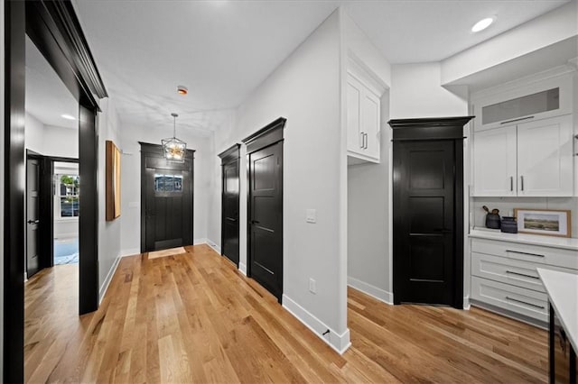 kitchen with white cabinets, light wood-style flooring, baseboards, and light countertops