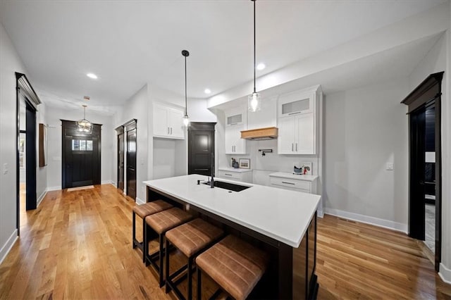 kitchen with a sink, baseboards, white cabinets, and recessed lighting