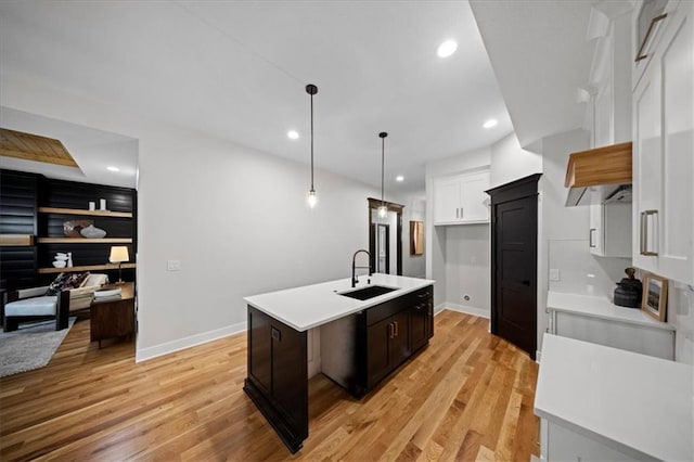 kitchen with a sink, light countertops, light wood-style flooring, and recessed lighting