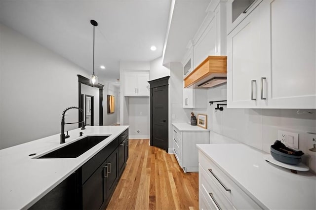 kitchen featuring a sink, dark cabinetry, white cabinetry, light countertops, and recessed lighting