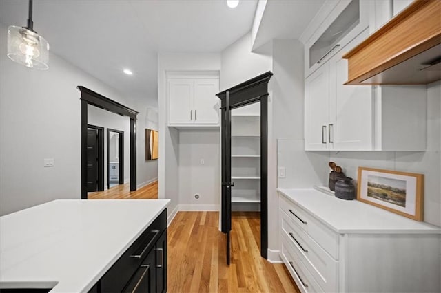 kitchen featuring white cabinets, custom range hood, recessed lighting, dark cabinetry, and light countertops