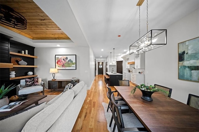dining room with light wood finished floors, recessed lighting, a chandelier, a tray ceiling, and wood ceiling