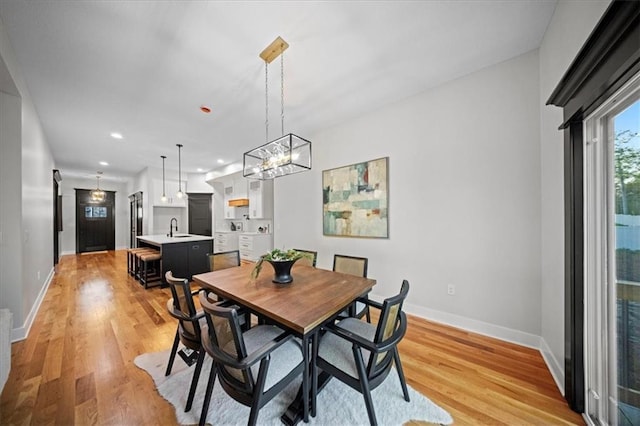 dining area with baseboards, light wood finished floors, recessed lighting, and a chandelier