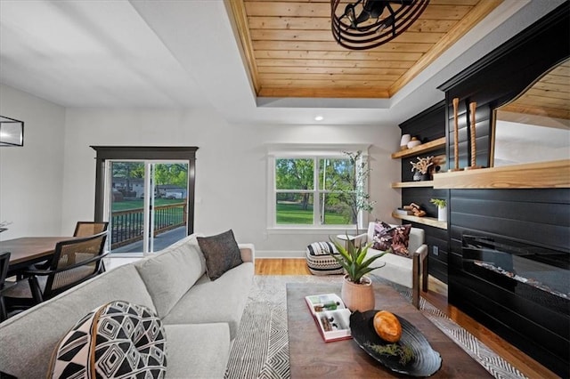 living room with wood finished floors, a raised ceiling, wood ceiling, and baseboards