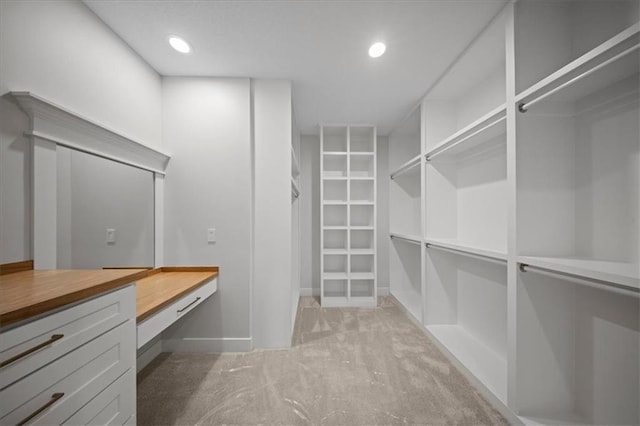 spacious closet featuring light colored carpet and built in study area