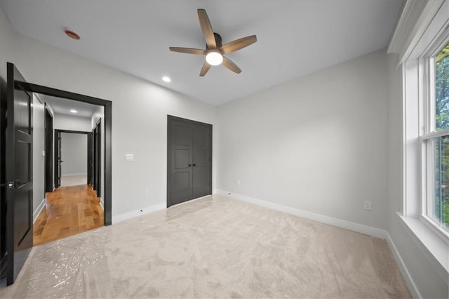 unfurnished bedroom featuring multiple windows, carpet, baseboards, and recessed lighting