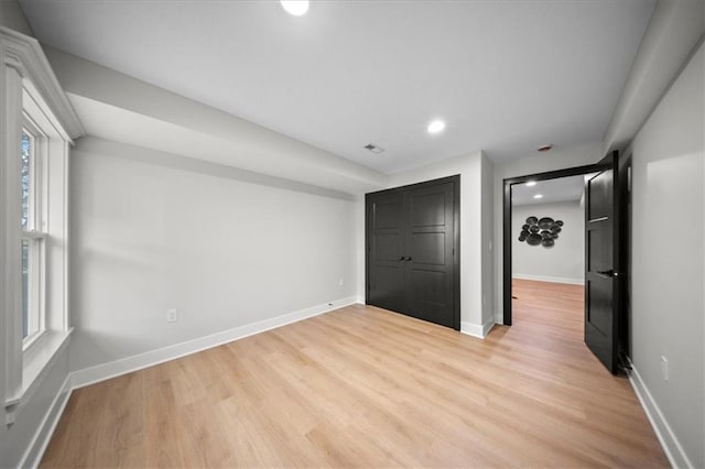unfurnished bedroom with light wood-type flooring, baseboards, recessed lighting, and a closet