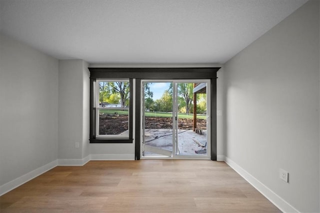 doorway featuring healthy amount of natural light, light wood-style floors, and baseboards