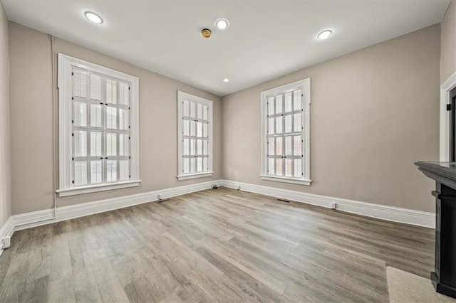 unfurnished living room featuring baseboards, recessed lighting, and wood finished floors