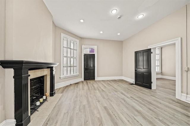unfurnished living room with baseboards, a fireplace, recessed lighting, and wood finished floors