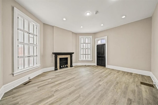 unfurnished living room with visible vents, wood finished floors, baseboards, recessed lighting, and a fireplace with flush hearth