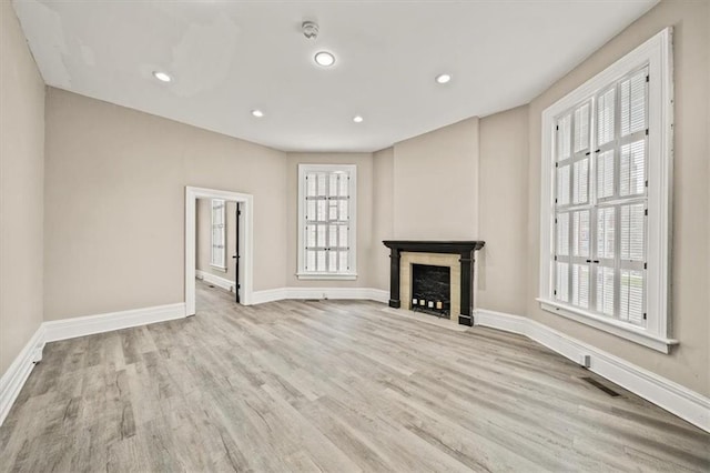 unfurnished living room with baseboards, a fireplace with flush hearth, wood finished floors, and recessed lighting