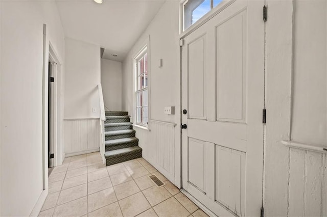 foyer featuring visible vents, light tile patterned floors, a wainscoted wall, and a wealth of natural light