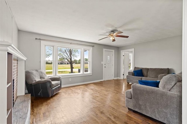 living area featuring baseboards, a ceiling fan, and wood finished floors