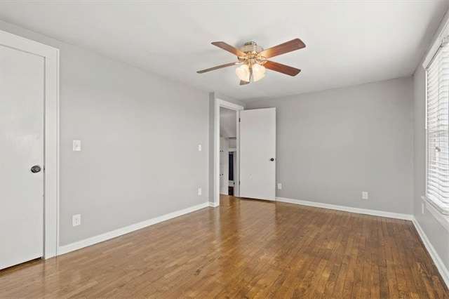 unfurnished room with a ceiling fan, baseboards, hardwood / wood-style flooring, and a healthy amount of sunlight