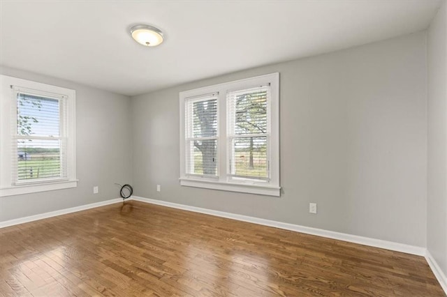 spare room with baseboards and wood finished floors