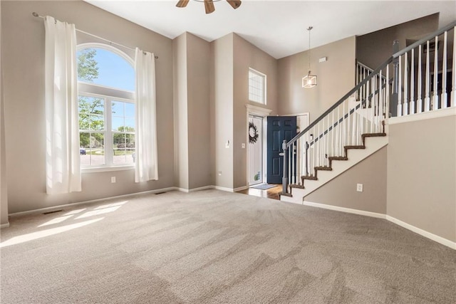 foyer entrance featuring baseboards, carpet flooring, stairs, and a high ceiling