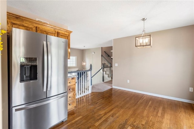 kitchen with pendant lighting, a notable chandelier, dark wood finished floors, and stainless steel fridge