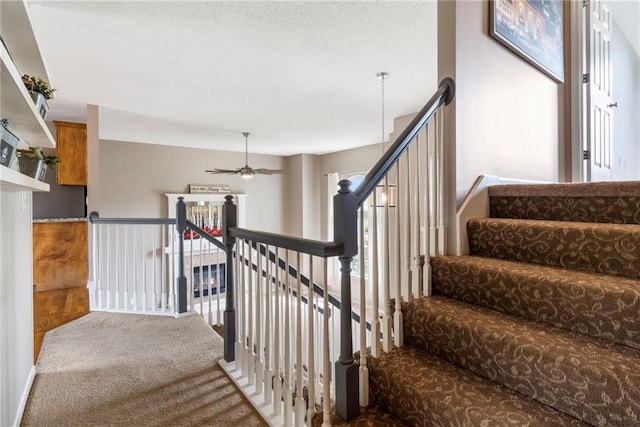 stairway with ceiling fan and carpet