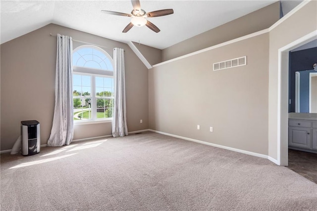 spare room featuring a ceiling fan, visible vents, carpet floors, baseboards, and lofted ceiling