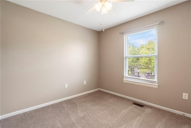 spare room with baseboards, ceiling fan, visible vents, and light carpet