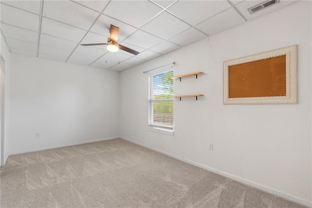 empty room featuring carpet flooring, ceiling fan, baseboards, a drop ceiling, and visible vents