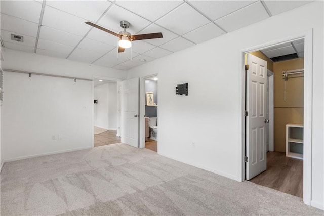 interior space featuring baseboards, ceiling fan, carpet, and a drop ceiling