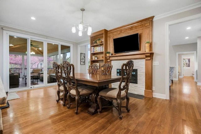10863 S Cedar Niles Cir, Olathe, KS 66061 - dining area with crown molding, a chandelier, wood finished floors, a stone fireplace, and baseboards