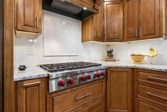 10863 S Cedar Niles Cir, Olathe, KS 66061 - kitchen with stainless steel gas cooktop, premium range hood, tasteful backsplash, brown cabinets, and light stone counters