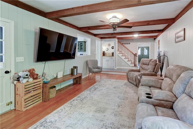 1400 SW 8th Ter, Lees Summit, MO 64081 - living room featuring stairs, light wood-style floors, a ceiling fan, wood walls, and beamed ceiling