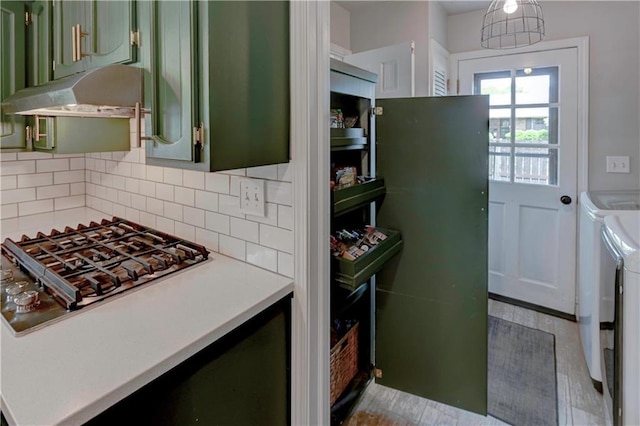1400 SW 8th Ter, Lees Summit, MO 64081 - kitchen with green cabinetry, washing machine and clothes dryer, under cabinet range hood, decorative backsplash, and light countertops