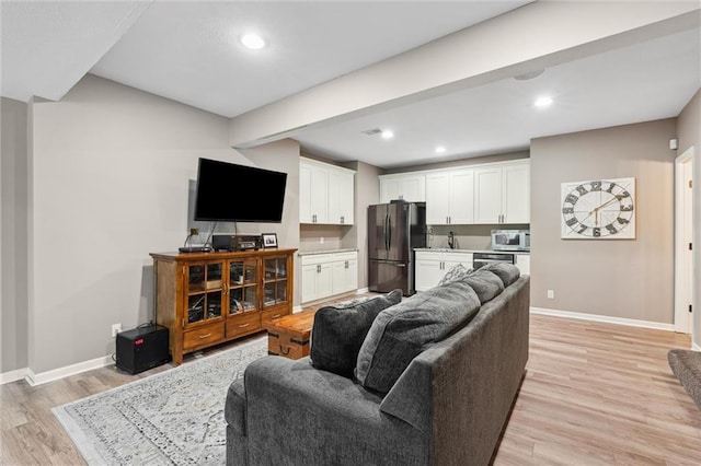 living area with baseboards, recessed lighting, and light wood-style floors