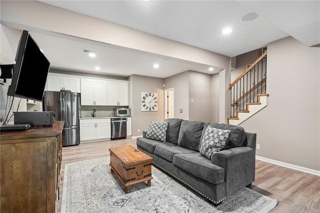 living area featuring stairs, recessed lighting, baseboards, and light wood finished floors