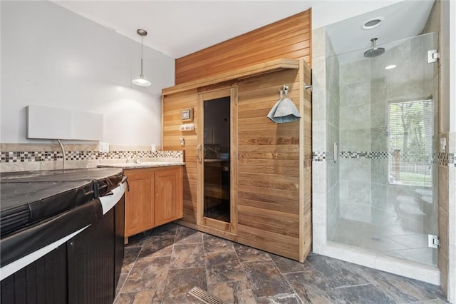 kitchen with brown cabinetry, hanging light fixtures, tasteful backsplash, wood walls, and a sauna