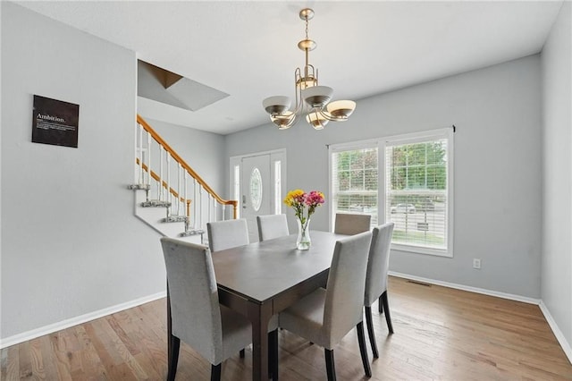 3945 SW Batten Dr, Lees Summit, MO 64082 - dining space with light wood-type flooring, baseboards, a chandelier, and stairway