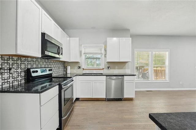 3945 SW Batten Dr, Lees Summit, MO 64082 - kitchen with stainless steel appliances, light wood-style flooring, plenty of natural light, and white cabinets