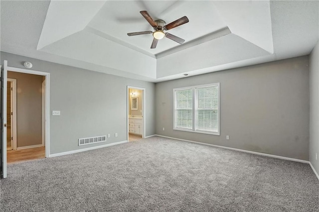 3945 SW Batten Dr, Lees Summit, MO 64082 - unfurnished bedroom with a raised ceiling, carpet floors, baseboards, and connected bathroom