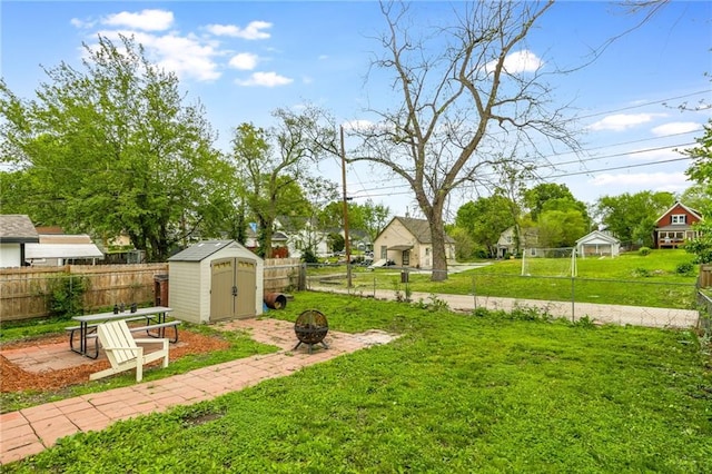 view of yard featuring a fenced backyard, an outbuilding, an outdoor fire pit, and a storage shed