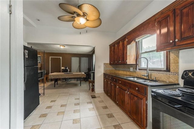 kitchen with dark countertops, a sink, backsplash, light tile patterned floors, and black / electric stove