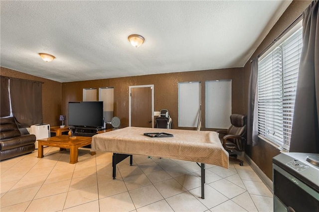 recreation room with a textured ceiling and light tile patterned floors