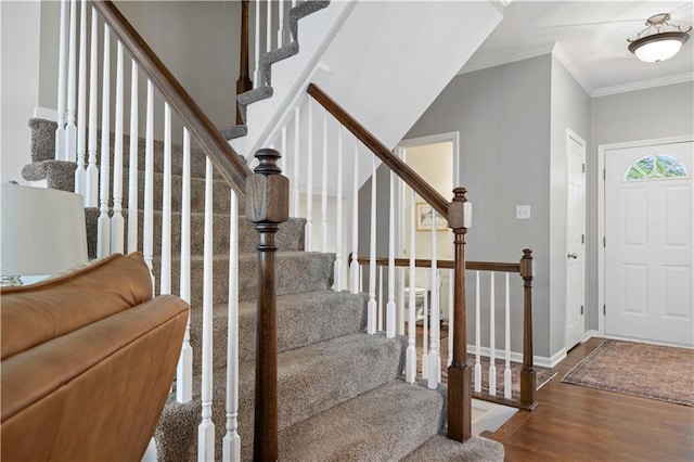 foyer entrance with stairway, baseboards, crown molding, and wood finished floors