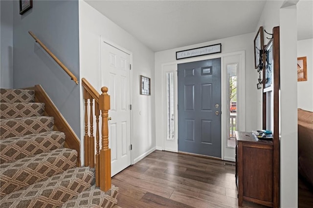 foyer entrance with stairs, baseboards, and wood finished floors