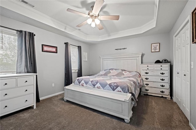 bedroom featuring visible vents, ornamental molding, dark colored carpet, a raised ceiling, and a ceiling fan